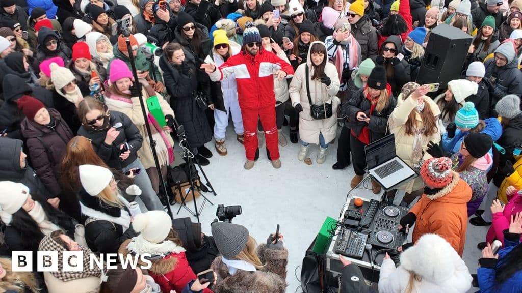 A wide shot of a crowd of people in heavy winter coats dancing on a frozen river in Kyiv, gray winter sky, ice texture, urban background, photorealistic, high contrast, mood is gritty but energetic.