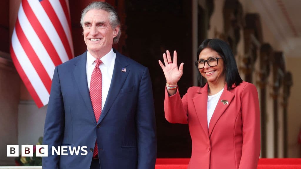 A gritty, cynical political cartoon style image. A large, menacing eagle wearing a suit and sunglasses is shaking hands with a headless suit or a puppet. In the background, oil barrels are stacked up. The mood is dark and satirical. High contrast.