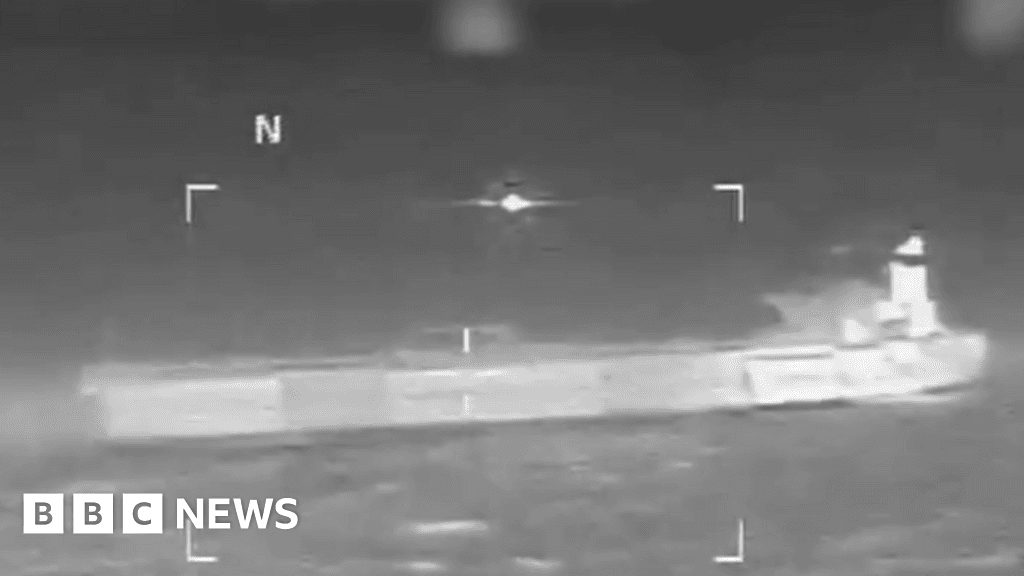 A gritty, satirical digital painting of a massive US Navy destroyer towing a rusted, old oil tanker named 'Veronica' through a dark, turbulent Caribbean sea at night. On the deck of the tanker, a giant, bloated Uncle Sam figure in a tattered suit is lounging in a lawn chair, holding a clipboard and looking bored. The lighting is cinematic and moody, with harsh searchlights cutting through the mist, highlighting the contrast between the high-tech warship and the decaying tanker. The atmosphere is cynical and industrial.