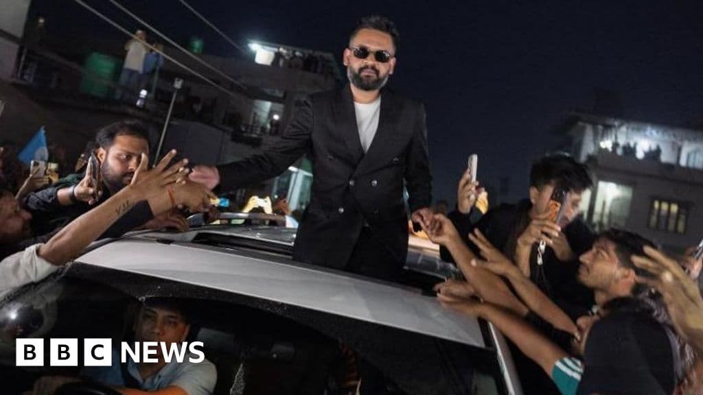 A gritty, cinematic photo of a street in Kathmandu, Nepal. On a crumbling brick wall, there is a vibrant, modern election poster of Balendra Shah wearing sunglasses, contrasted sharply against faded, torn political graffiti and signs of past unrest. The lighting is moody and natural, capturing a sense of cynical hope amidst decay.