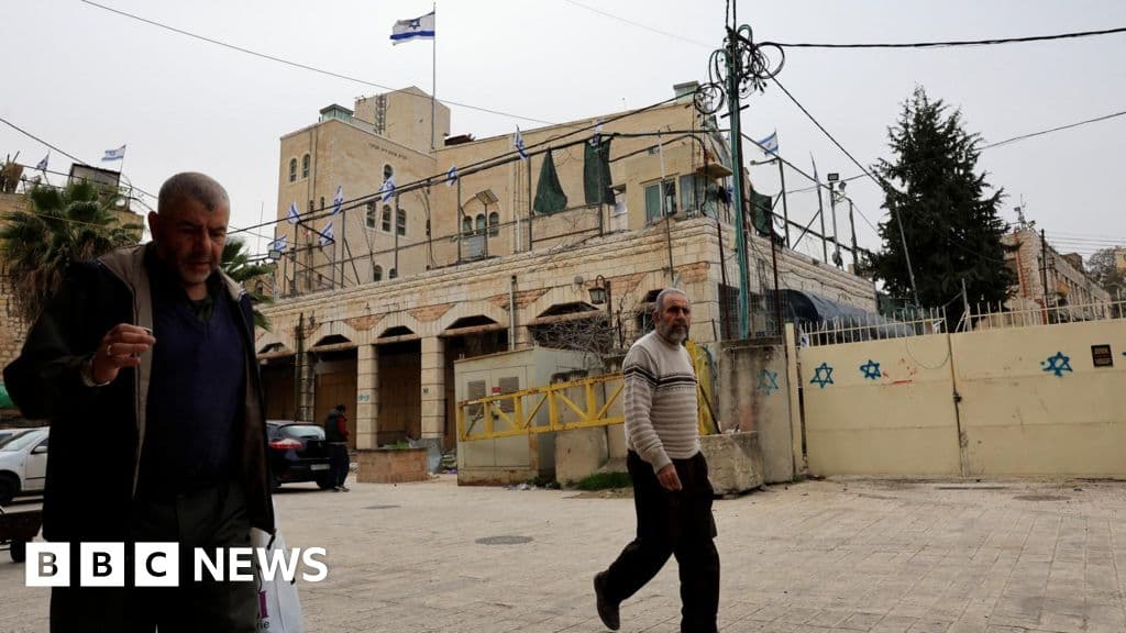 A gritty, high-contrast photo of a stack of legal paperwork and a gavel resting on a dusty, torn map of the West Bank. The lighting is harsh and dramatic, emphasizing the texture of the paper and the stone. No people, just the oppressive weight of bureaucracy.