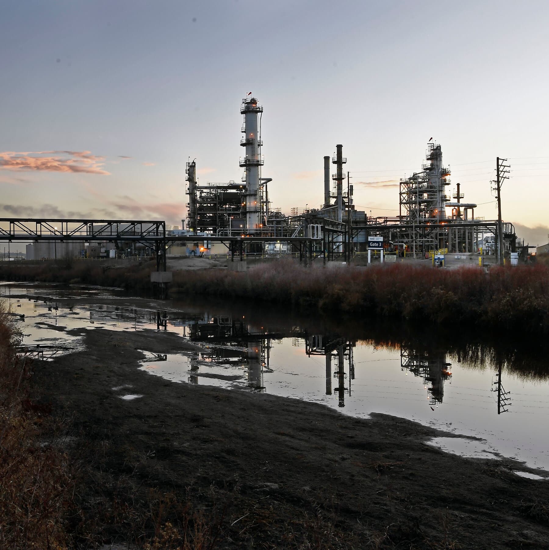 A highly cynical, satirical illustration showing a giant, overflowing oil barrel wearing a judge's wig and holding a gavel, crushing a tiny, flooding city. In the background, suited lawyers and politicians from both sides are eagerly catching falling money while standing in knee-deep water. The style should be gritty, caricature-like, and dark.