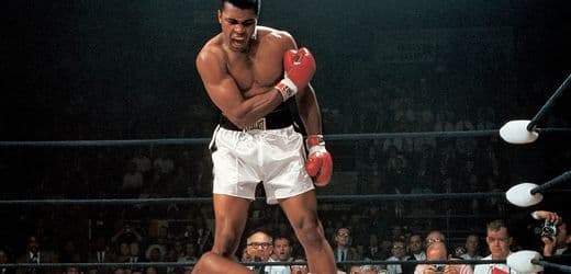 A high-contrast, cynical black and white photograph of a bored, middle-aged photographer in a tuxedo, looking away from a boxing ring in disgust while holding an old Rolleiflex camera. In the background, two blurry figures are in a boxing match, illuminated by a harsh, cold strobe light. The atmosphere is one of intellectual disdain and clinical detachment.