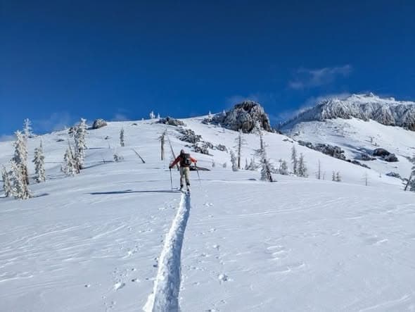 A vast, stark landscape of the Austrian Alps covered in deep white snow, dark storm clouds gathering above, a small bright orange rescue helicopter in the distance, a yellow avalanche warning sign in the foreground half-buried in snow, high contrast, moody atmosphere.