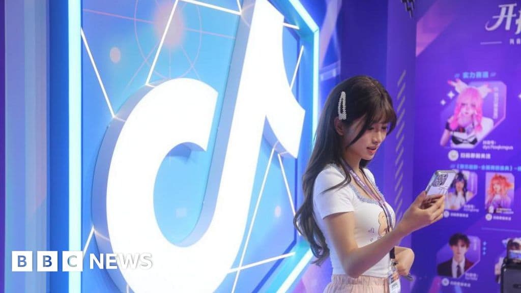 A satirical political cartoon style image showing two giant, clumsy looking bureaucrats in suits, one wearing an Uncle Sam hat and the other a generic authoritarian uniform, fighting over a glowing smartphone. The smartphone screen shows a silly dancing figure. In the background, a wall is being built through the middle of a computer circuit board. The lighting is dramatic and moody.