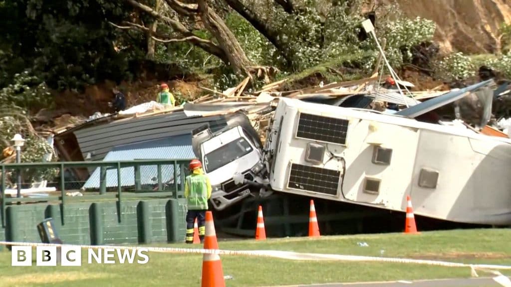 A satirical illustration of a politician in a suit standing waist-deep in mud, shouting into a microphone and pointing accusingly at a rain cloud, while a landslide destroys a house in the background. The style should be dark, moody, and cynical.