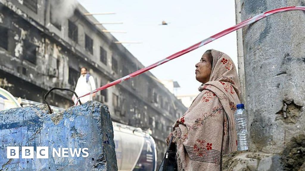 A gritty, realistic scene of a smoldering concrete building in Karachi, grey smoke rising into a hazy sky, worn-out fire trucks in the foreground, cynical atmosphere, muted colors