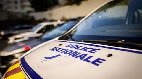 A moody, noir-style illustration of an empty classroom in France. In the center, a single wooden desk sits under a harsh spotlight. On the desk, instead of a book, there is a sharp, jagged shadow cast by an unseen object. The atmosphere is cold, blue, and cynical. No people, just the eerie silence of a crime scene in a place of learning.