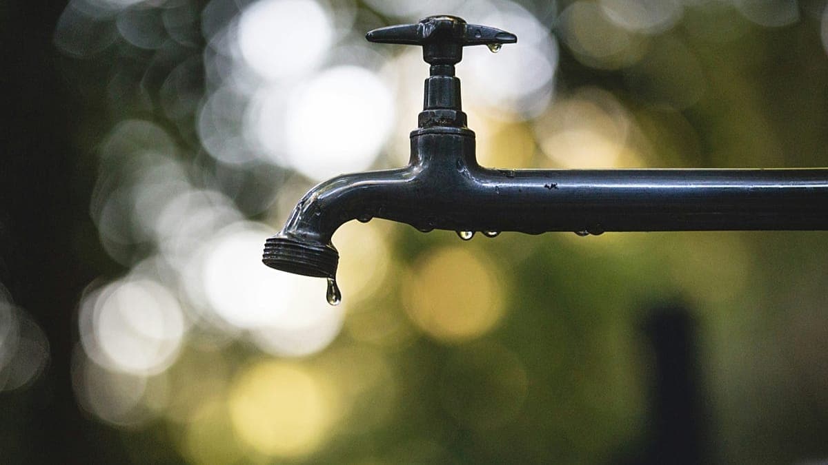 A hyper-realistic, bleak image of a gilded, empty UN assembly hall where the floor has turned into cracked, parched earth, with a single, rusted gold faucet dripping a drop of oil instead of water into a dusty, dry glass.
