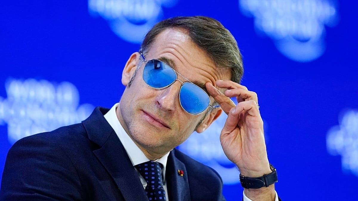 A highly detailed, cynical editorial illustration of Emmanuel Macron wearing oversized, highly reflective aviator sunglasses at a Davos podium. The reflection in the lenses shows a distorted, fiery landscape of protesting crowds, while he stands in a cold, blue-tinted Swiss Alpine setting. His expression is one of aloof, intellectual disdain. The art style is sharp, clean, and satirical, reminiscent of high-end European political cartoons.