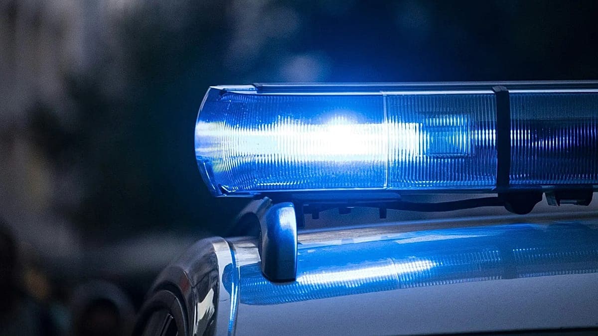 A gritty, satirical digital painting of two suspicious men in drab tracksuits, one holding a grainy smartphone and the other a crumpled map of a military base. They are standing in a grey, rainy Berlin street with the Brandenburg Gate in the distance. Above them, a giant, looming German bureaucrat holds a massive, outdated fax machine like a weapon, while a Russian bear and an American eagle glare at each other in the background. High contrast, dark charcoal and sickly yellow color palette.