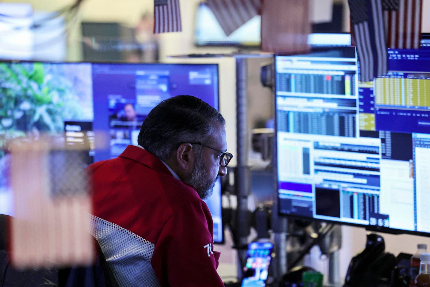 A satirical oil painting in the style of 18th-century political cartoons. A giant, orange-tinted man in a suit stands on a map of the world, trying to pry a piece of ice labeled 'Greenland' off the map with a gold-plated golf club. Across the ocean, a group of powdered-wig bureaucrats in blue and gold robes throw blocks of cheese and wine bottles at him. In the foreground, a stock market ticker tape is drowning in a literal sea of red ink, while tiny investors in suits fall off a cliff into a void.