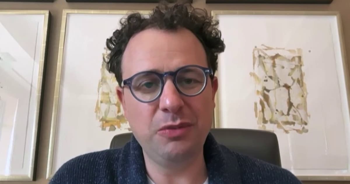 A moody, cynical illustration of a tech CEO in a suit standing behind a podium giving a speech. Behind him, a giant, chaotic robot shadow looms over a crowd of small, confused people. The lighting is dark blue and grey, emphasizing a sense of sophisticated dread.