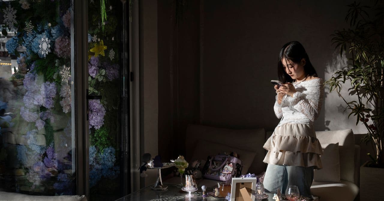 A hyper-realistic, cynical photograph of a woman sitting in a sterile, neon-lit Chinese cafe. She is staring intensely at a man dressed in elaborate, silver-haired anime cosplay. The man looks stiff and robotic, his eyes blank and vacant, wearing a 'Love and Deepspace' style outfit. In the foreground, a smartphone lies on the table showing a 2D anime version of the same man. The lighting is cold, blue, and artificial, emphasizing a sense of profound loneliness and technological alienation.