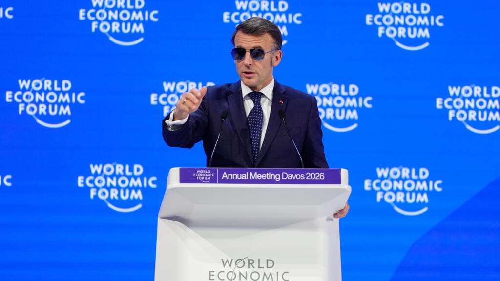 A cynical editorial cartoon style. A tiny, melting Greenland iceberg in the middle of a dark ocean. On one side, a miniature Napoleon-style Emmanuel Macron stands on a toy NATO ship, looking through a telescope. On the other side, a giant, orange-tinted Donald Trump is trying to stick a 'SOLD' sign into the melting ice. In the background, wealthy people in suits at Davos are watching through binoculars while sipping champagne. High contrast, sharp lines, acidic colors.