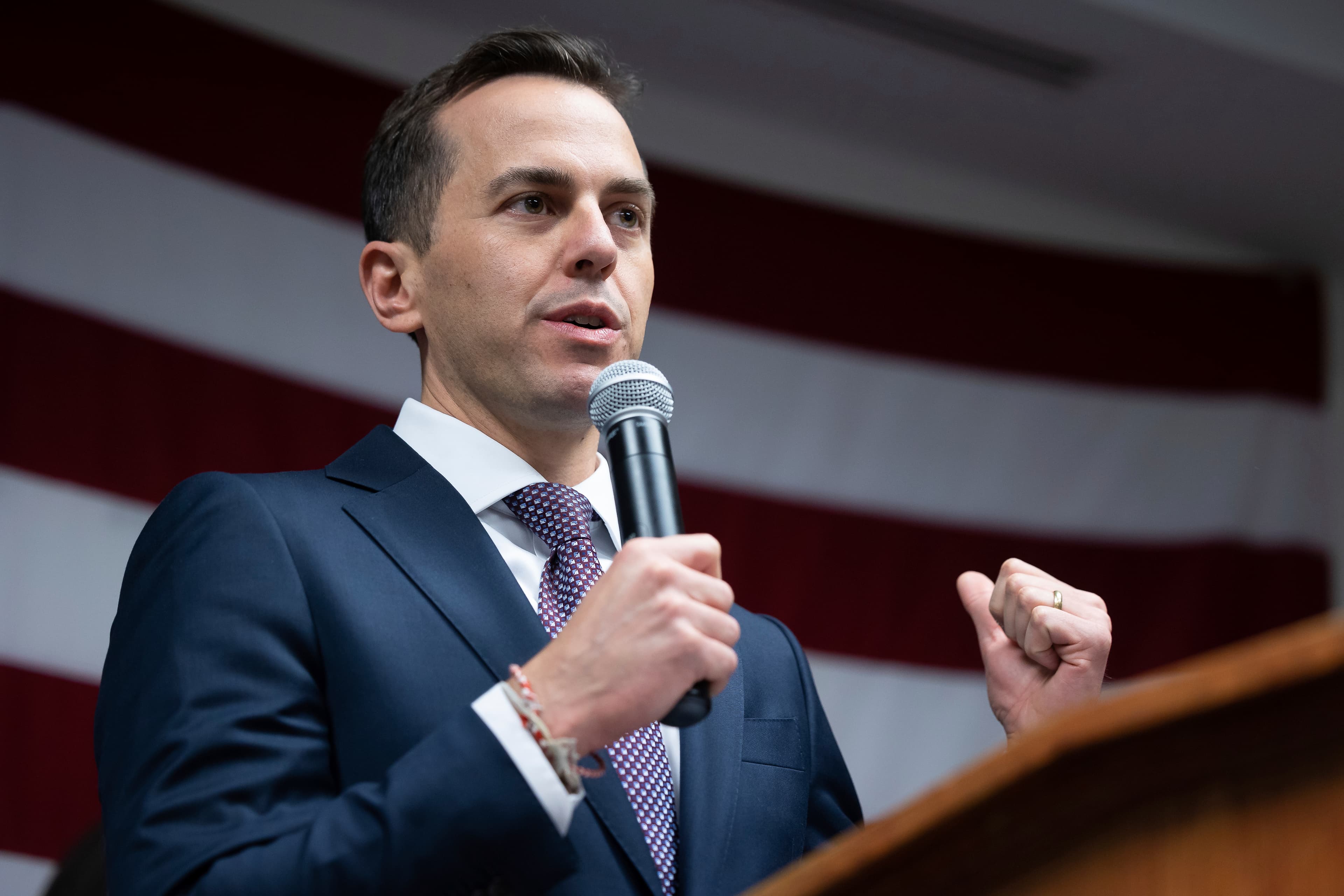 A dark satirical oil painting of two groups of faceless politicians in blue suits fighting over a tattered map of the Middle East inside a crumbling US Capitol building, with ballot boxes overflowing with burning money in the foreground, in the style of Honoré Daumier.