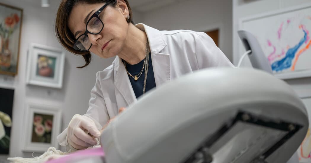 A gritty, satirical editorial illustration of an elderly doctor in a white coat sitting in a very cramped, dark broom closet. He is surrounded by mops, buckets, and high-tech medical monitors. The room is tiny, with peeling wallpaper. A neon sign outside the door says 'OFFICE SPACE FOR RENT'. The lighting is harsh and dramatic, high contrast, in the style of a cynical political cartoon.