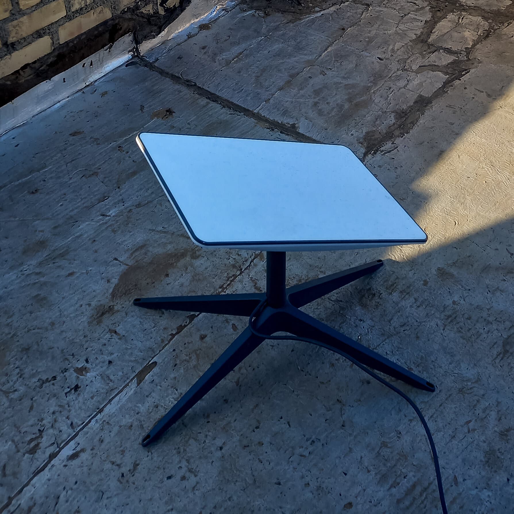 A satirical, photorealistic image of Iranian government officials standing on tall ladders in the desert, frantically trying to tape a massive, knitted quilt onto the the blue sky. In the background, a frustrated Ayatollah is holding a very long broomstick, trying to poke a satellite.
