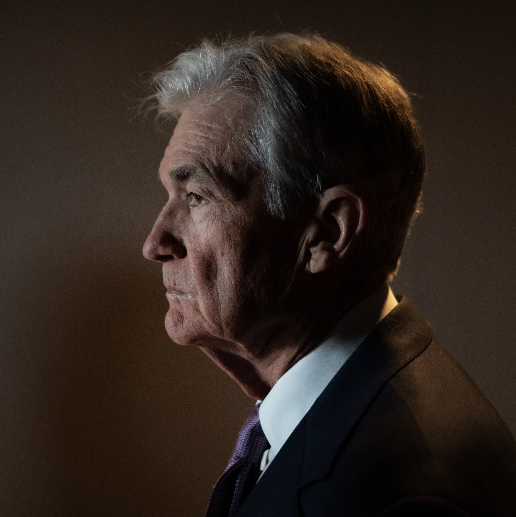 A hyper-realistic, satirical digital painting of Jerome Powell and Donald Trump. Powell is depicted as a stone-faced, grey-skinned statue made of compressed hundred-dollar bills, wearing a drab suit. Trump is depicted as a massive, orange, inflatable balloon figure with a megaphone. They are standing on opposite sides of a giant, crumbling scale that is weighing a single, wilted grocery bag against a pile of gold bars. The background is the interior of the Federal Reserve, but the walls are made of gold-plated filing cabinets and the floor is a sea of red ink. The lighting is cold, sterile, and overly dramatic.