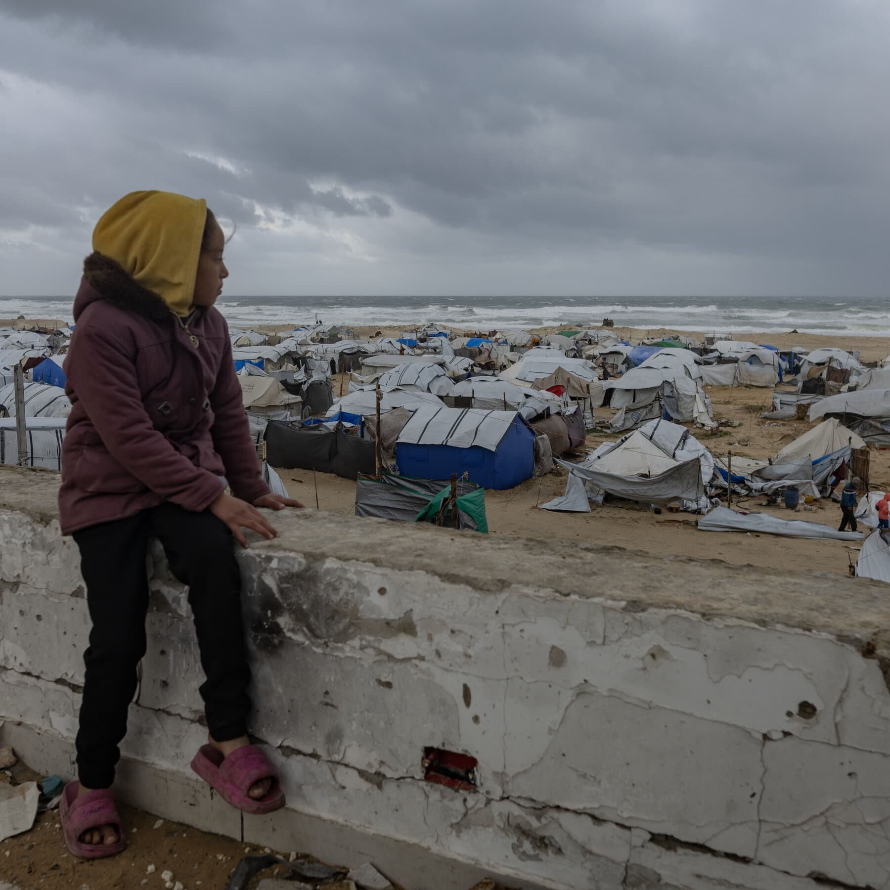 A photorealistic news photo of Donald Trump sitting at the head of a gaudy, gold-plated boardroom table, gesturing wildly at a confused Emmanuel Macron and Keir Starmer. Trump is holding up a blueprint labeled 'Gaza Tower & Casino,' while the world leaders wear oversized red hats that say 'BOARD MEMBER'.