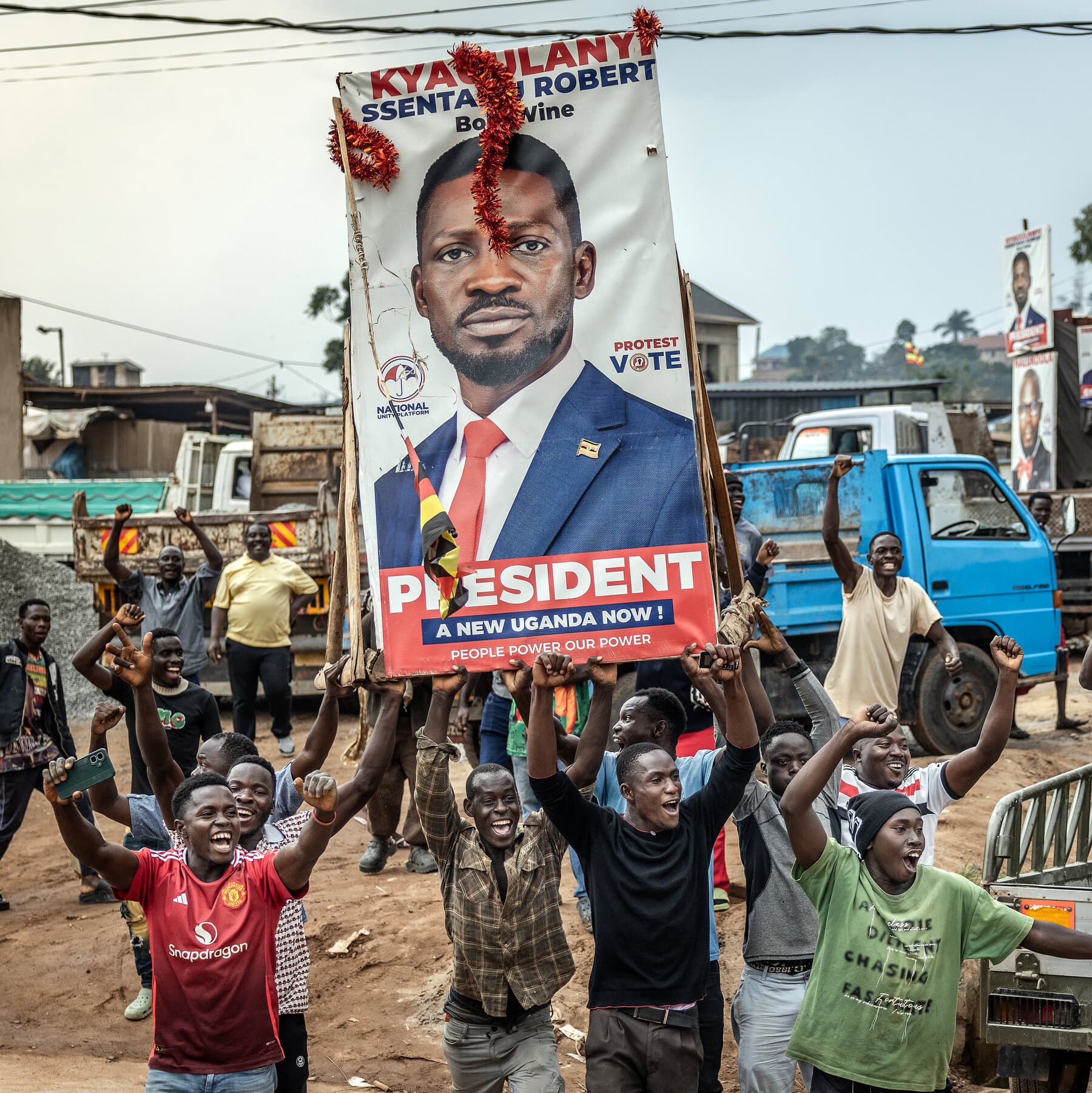 A satirical illustration in the style of a news photo showing a heavily armed military helicopter landing in a residential garden. Ugandan soldiers dressed in camo but wearing bellhop hats are forcefully carrying a man who looks like Bobi Wine onto the chopper like he is a piece of luggage. A banner hanging from the helicopter reads 'VIP CONCIERGE SERVICE.' The sky is gray and ominous.