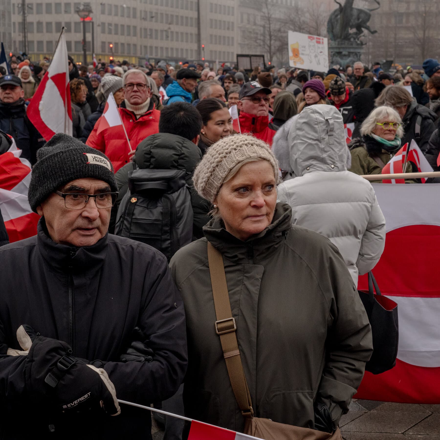 A photorealistic news image of the Little Mermaid statue in Copenhagen, but it has been vandalized with spray paint, covered in trash bags, and surrounded by burning tires, while a confused Donald Trump looks at it through a surveyor's tripod in the foreground.