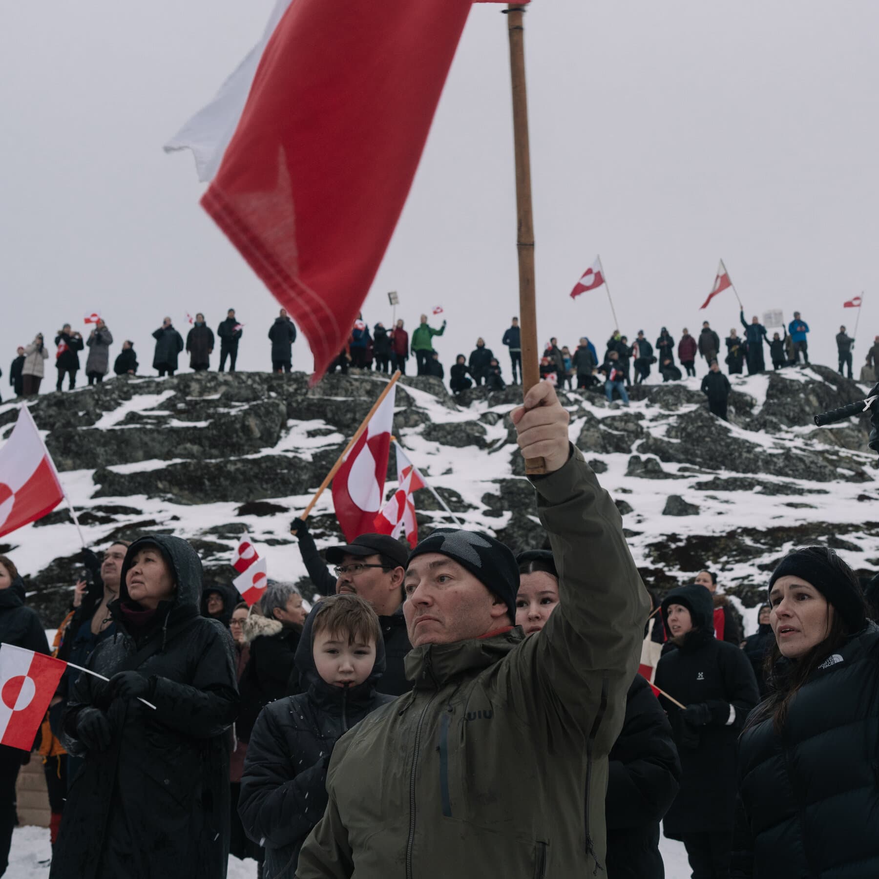 A photorealistic news image of European Commission President Ursula von der Leyen looking visibly terrified and sweating while pointing a bazooka made entirely of rolled-up paperwork and red tape at a map of the United States.