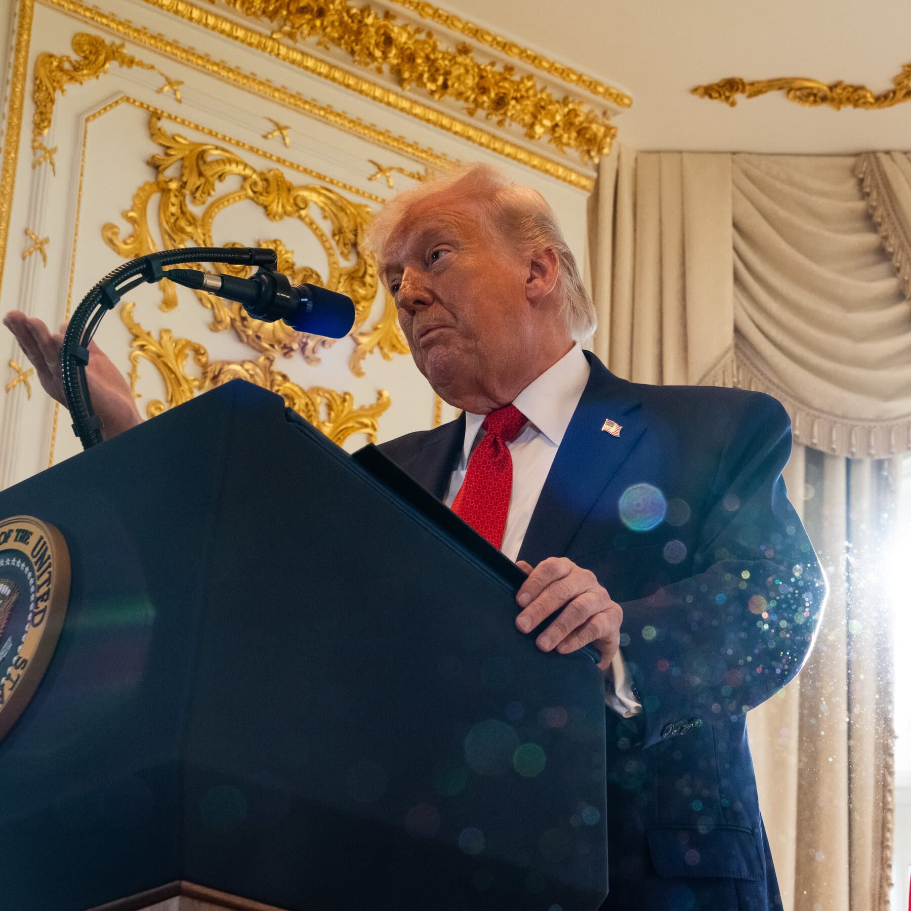 A satirical editorial illustration of a gold-plated real estate 'SOLD' sign stabbed into a melting glacier in Greenland, with a silhouette of a golden skyscraper reflecting in the rising ocean water, while tiny, faceless bureaucrats in suits stand on a nearby ice floe holding empty folders labeled 'Strategic Partnership'.