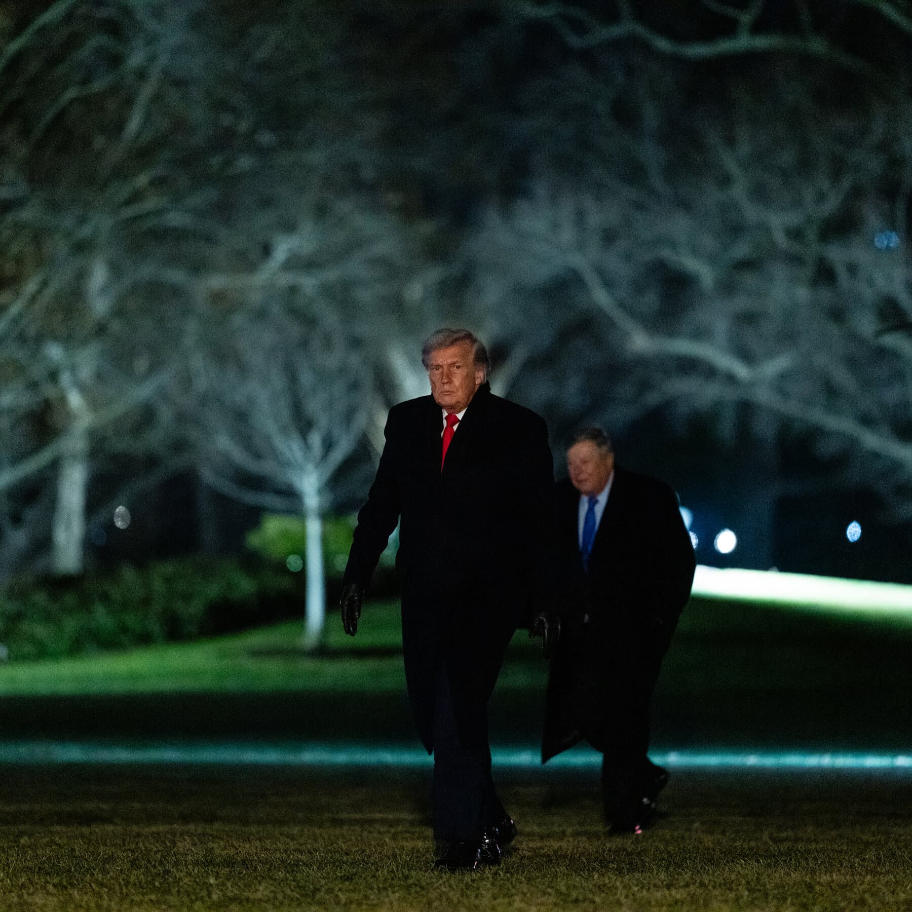 A photorealistic satirical image of Donald Trump on an airport tarmac wearing an oversized suit, laughing and giving a playful noogie to a distressed-looking Emmanuel Macron and Angela Merkel, while other European leaders in the background look down at their feet in shame. Air Force One is visible in the background with the engine running.