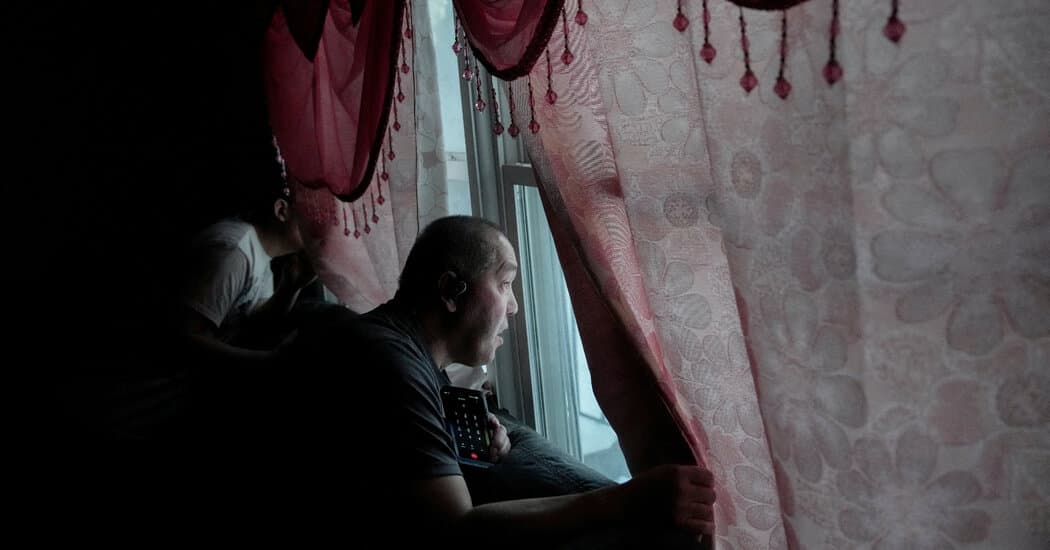 A satirical, high-contrast digital painting of a confused man holding a large, glowing U.S. passport while being surrounded by faceless ICE agents in heavy tactical gear. The agents are holding a 'Wanted' poster that shows a generic silhouette with a question mark. The background is a drab, bureaucratic hallway filled with stacks of overflowing paperwork and a 'Mission Accomplished' banner hanging crookedly.