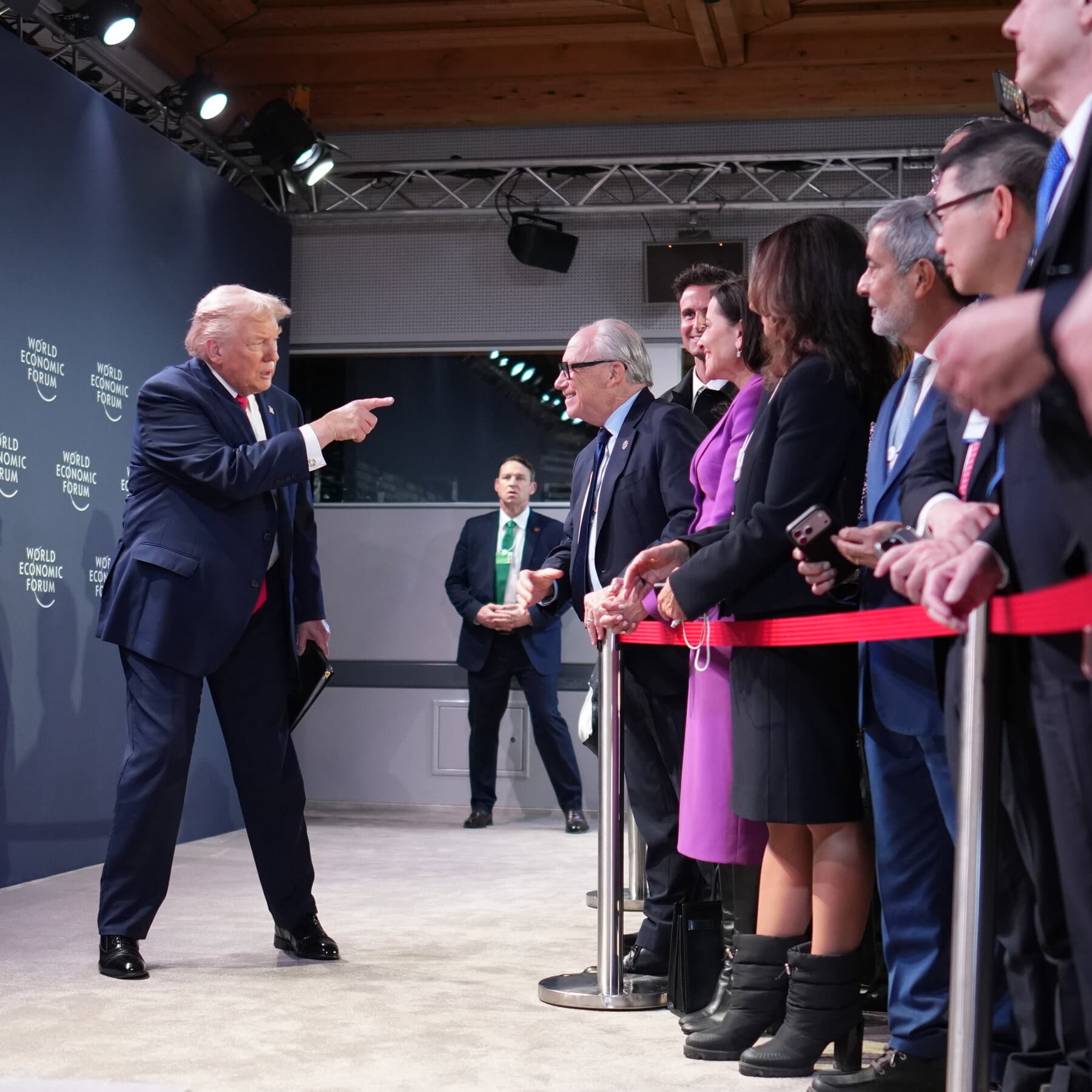 A hyper-realistic, cynical digital painting of a golden, cracking US Capitol dome being used as a literal top for a giant spinning 'whipsaw' toy. In the background, a row of European leaders in grey suits stand in a line, looking into their empty wallets with expressions of hollow despair. The lighting is harsh and theatrical, casting long shadows over a map of the world that is being torn apart by the centrifugal force of the spinning dome.