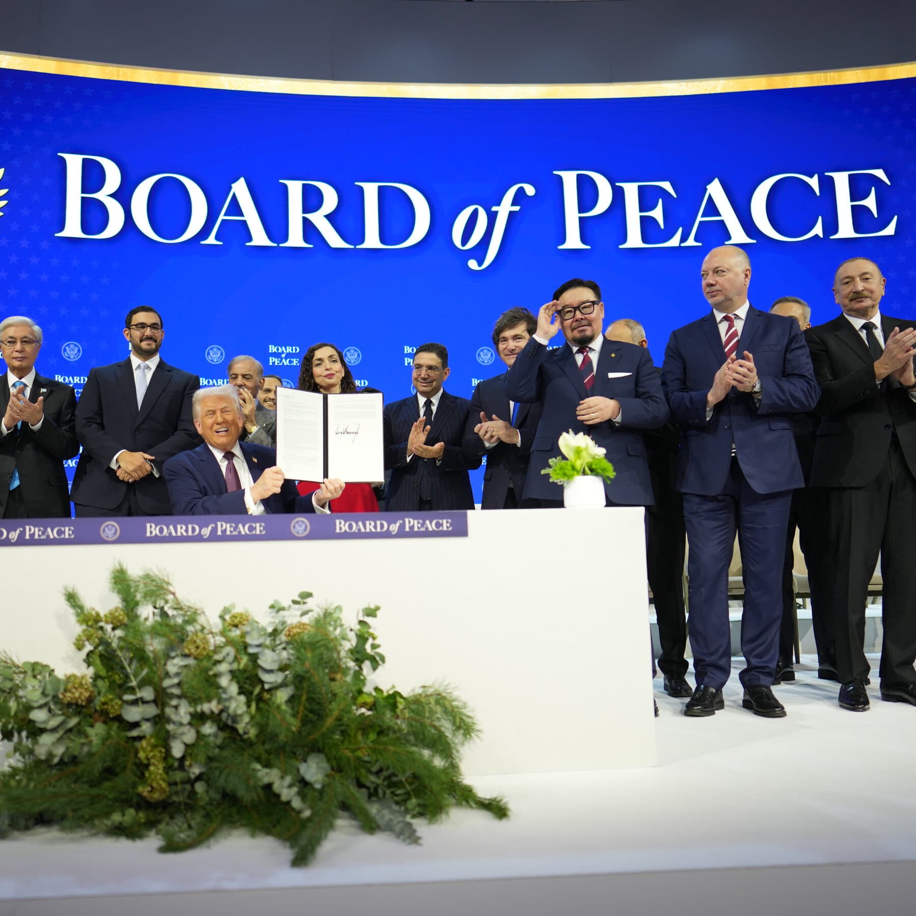 A satirical, hyper-realistic architectural rendering of a sleek, futuristic glass skyscraper rising incongruously out of a pile of smoking grey rubble. In the foreground, men in expensive suits examine a blueprint on a table, completely ignoring the destruction around them. The sky is a dystopian smoggy orange, but the building reflects a fake, bright blue sky.