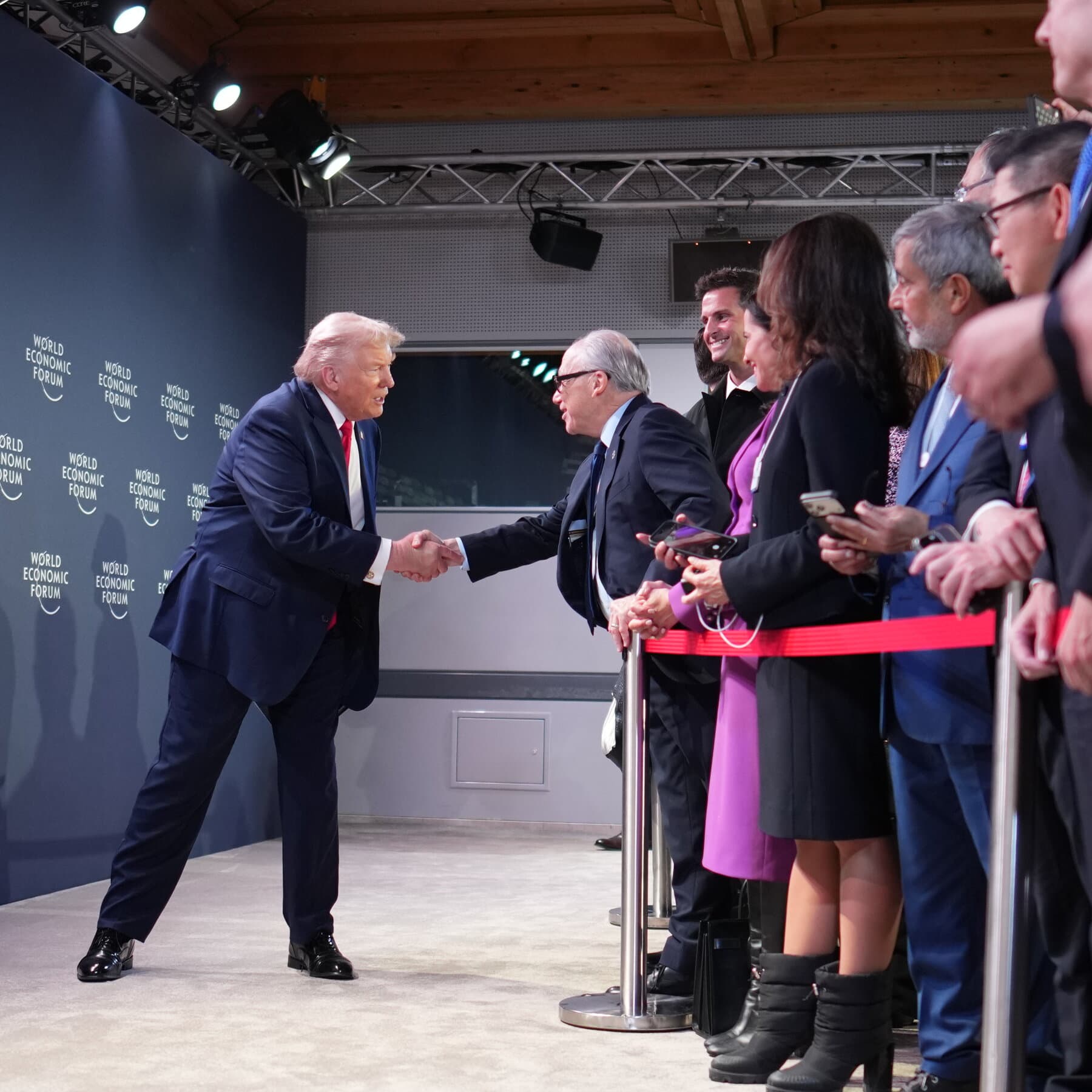 A satirical illustration of the Swiss Alps where the mountain peaks are made of gold bars. On the slopes, billionaires in expensive parkas are frantically using giant erasers to rub out words like 'Equality' and 'Green' from their private jets, while a massive, looming silhouette of a golden tie-wearing figure overlooks the valley. The style is sharp, cynical, and reminiscent of a high-end political cartoon.