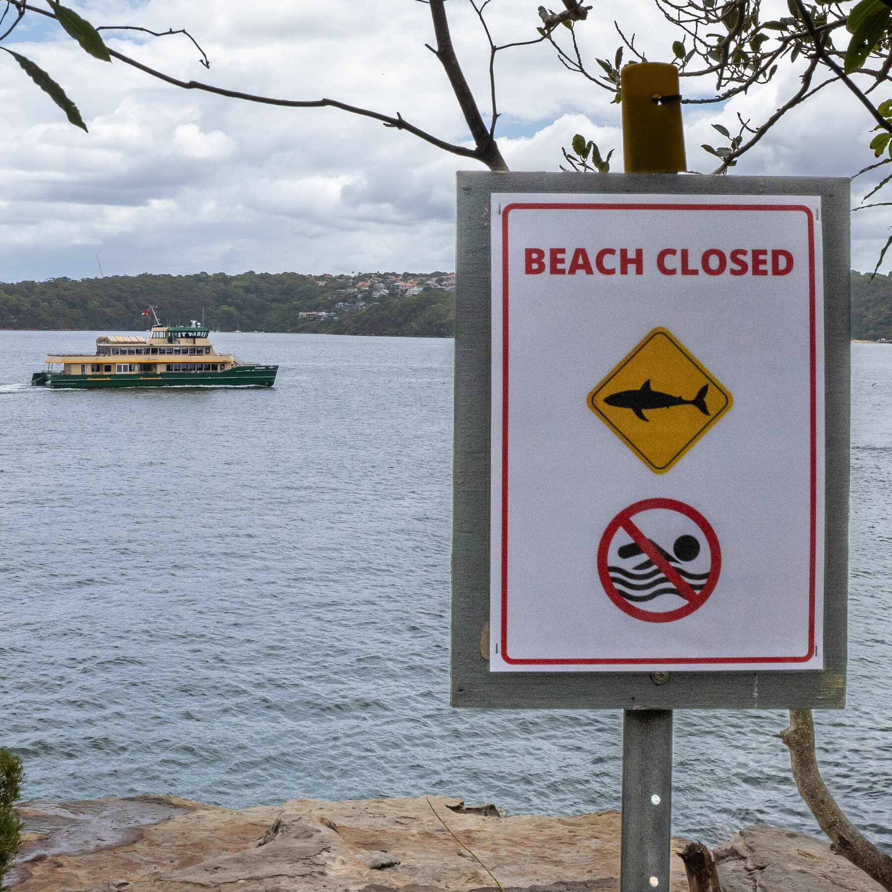 A lonely, deserted Australian beach under a bright, harsh sun. In the foreground, yellow police tape flutters in the wind, blocking access to the blue water. The scene is beautiful but unsettling, highlighting the contrast between a vacation paradise and a crime scene.