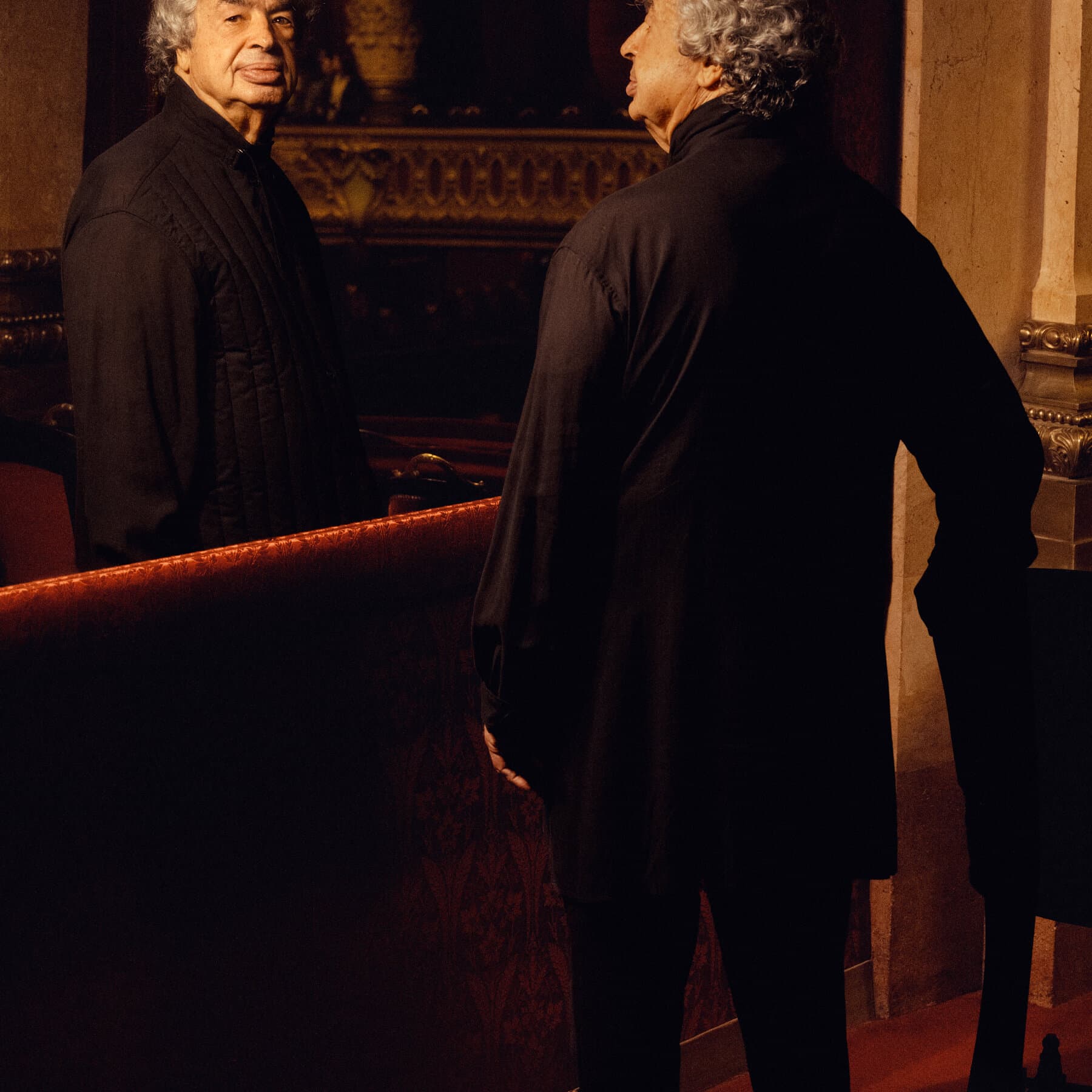 A satirical, hyper-realistic oil painting of a lavish opera house in decay. The conductor, an elderly man with a wild expression, is waving a baton made of a golden bone. The audience is comprised of skeletons in tuxedos and evening gowns, clapping politely. In the background, heavy red velvet curtains are tattered and smoking. The lighting is dim, golden, and ominous.