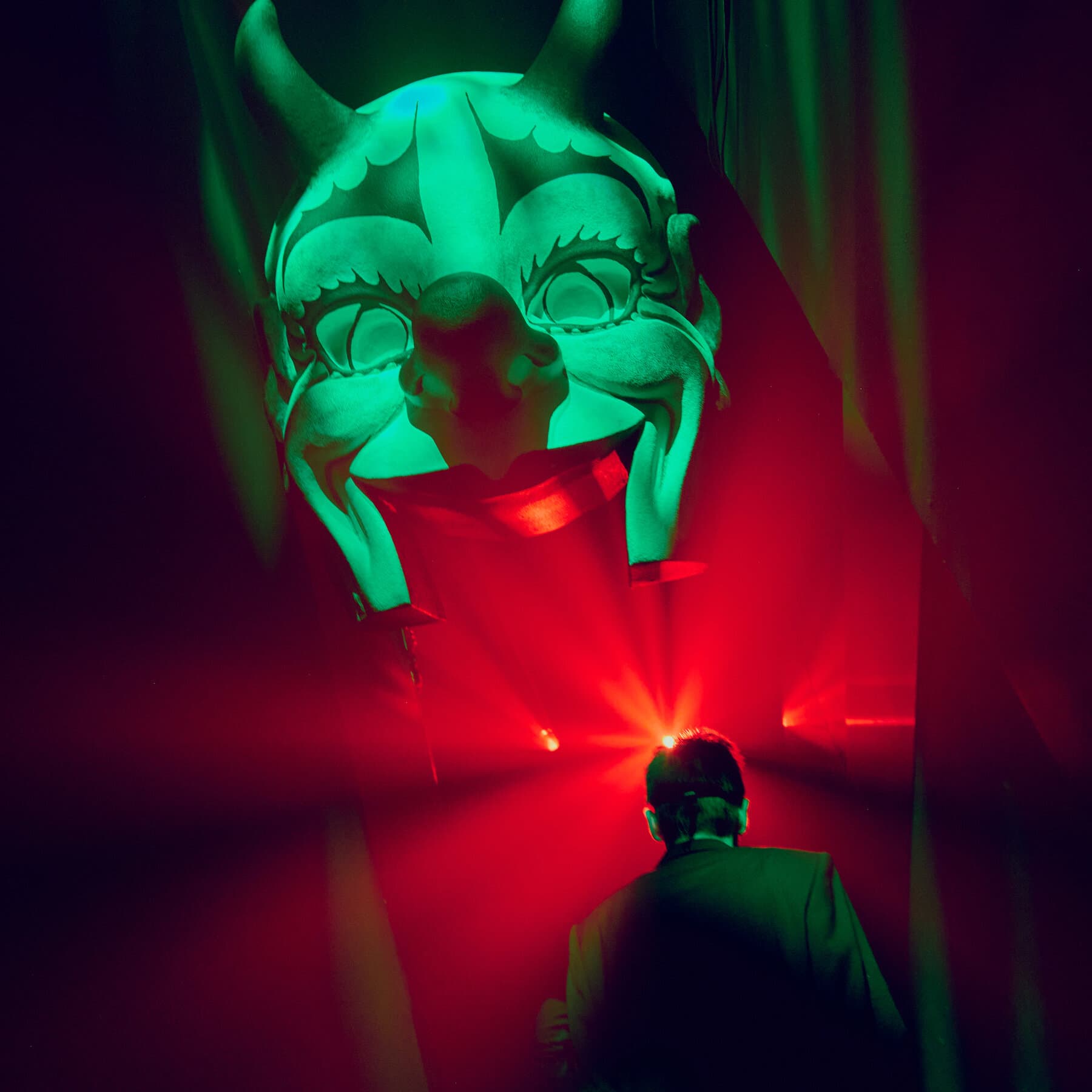 A hyper-realistic, dark satirical painting of a crowded, opulent New York ballroom filled with wealthy socialites wearing ornate masks, their faces underneath showing expressions of hollow-eyed boredom and vapidity. In the center, a distorted, spectral figure in a tuxedo looms, holding a glowing digital credit card reader like a holy relic. The lighting is sickly gold and deep shadows, style of Ralph Steadman meets Caravaggio.