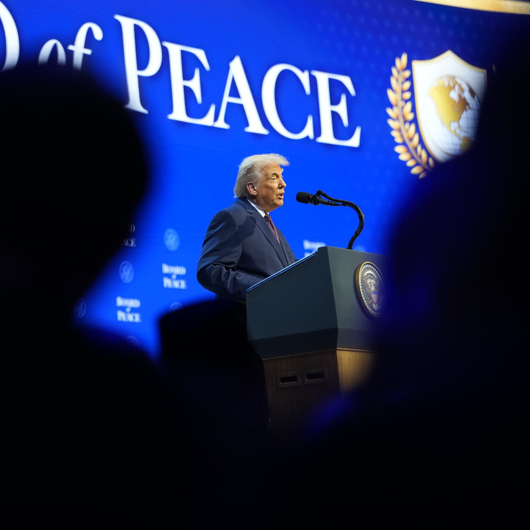 A wide shot of a dusty, abandoned boardroom table in the middle of a desert. On the table is a gold nameplate that says 'PEACE' which is rusting and falling off the edge. There are papers blowing away in the wind. The sky is grey and ominous. High contrast, gritty, realistic style.