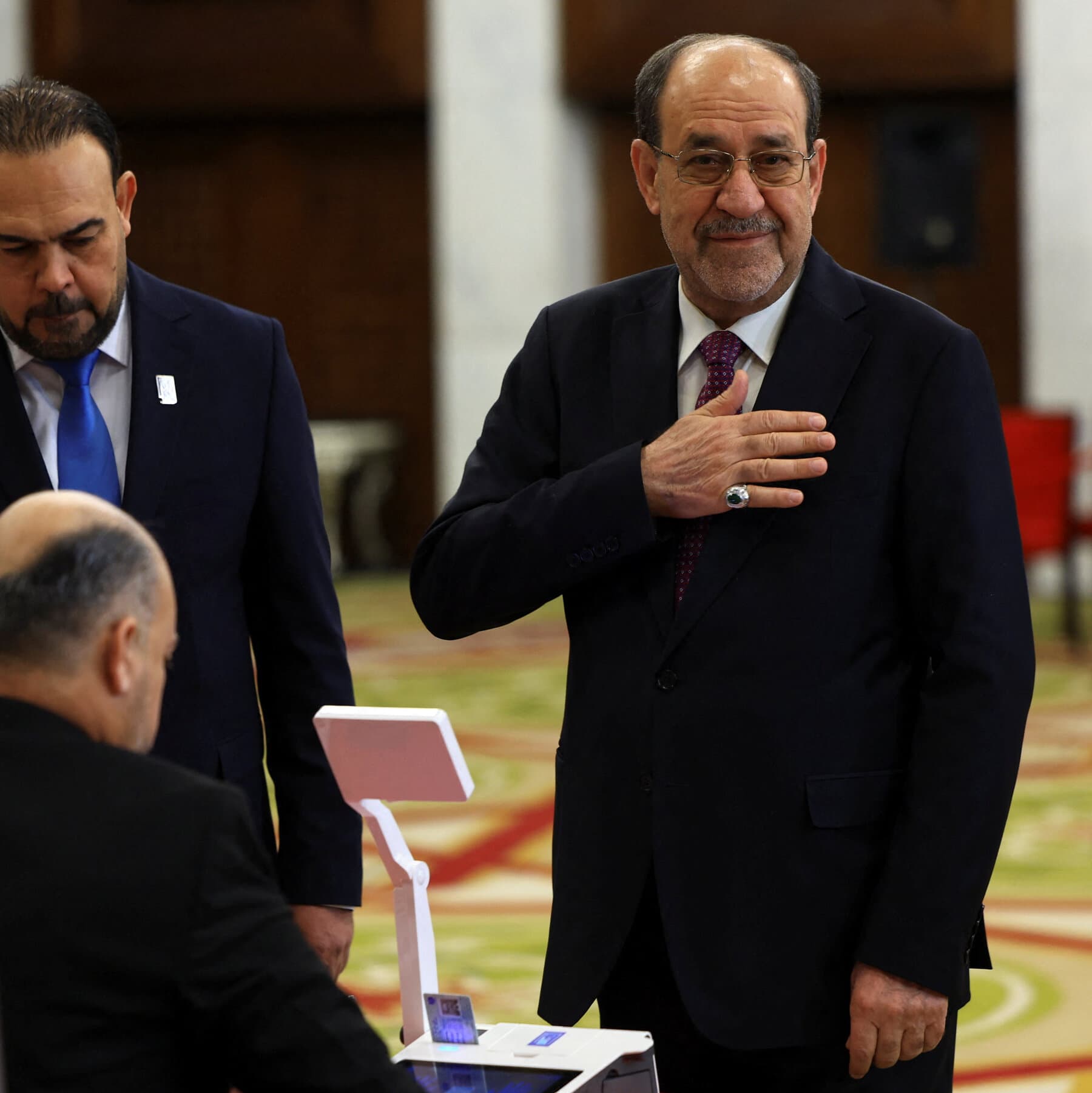 A conceptual, gritty illustration showing a chessboard in the middle of a desert. On one side, a giant hand in a business suit is trying to knock over a chess piece. On the other side, the chess piece is made of stone and refuses to move. In the background, there are faded flags and dust storms. The style should be cynical and shadowed, reflecting political stalemate.