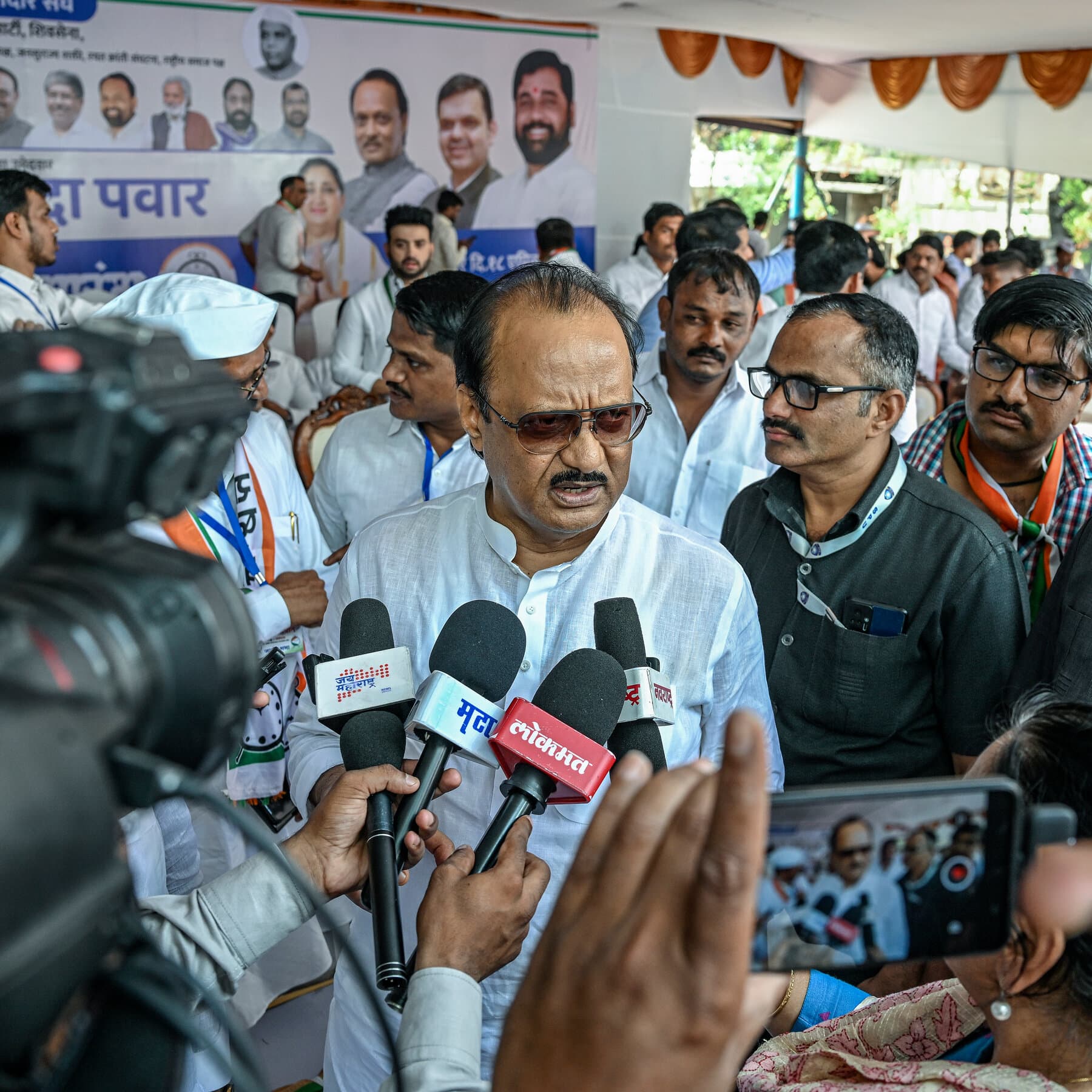 A gritty, noir-style illustration of a broken private jet wing lying in tall grass under heavy rain. In the foreground, a torn, wet political campaign poster of an Indian politician flaps in the wind, half-buried in mud. Muted colors, dark blues and greys, focusing on the decay of power and machinery.
