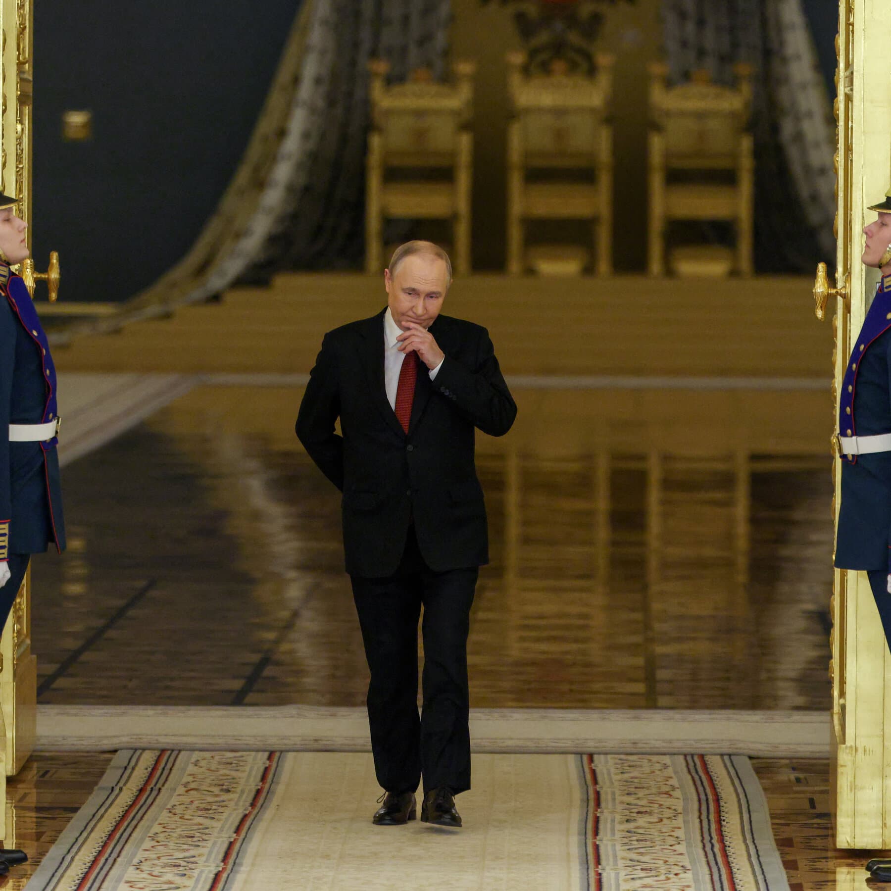 A gritty, cynical illustration in a satirical political cartoon style. The image depicts a large, shadowy figure resembling a puppet master in a suit, sitting at a table in Moscow. In one hand, he holds a marionette doll that looks like the new leader, shaking it by the hand. In his other hand, behind his back, he holds a broken marionette doll representing the old leader. The background is a cold, grey Kremlin office. The atmosphere is gloomy and sarcastic.