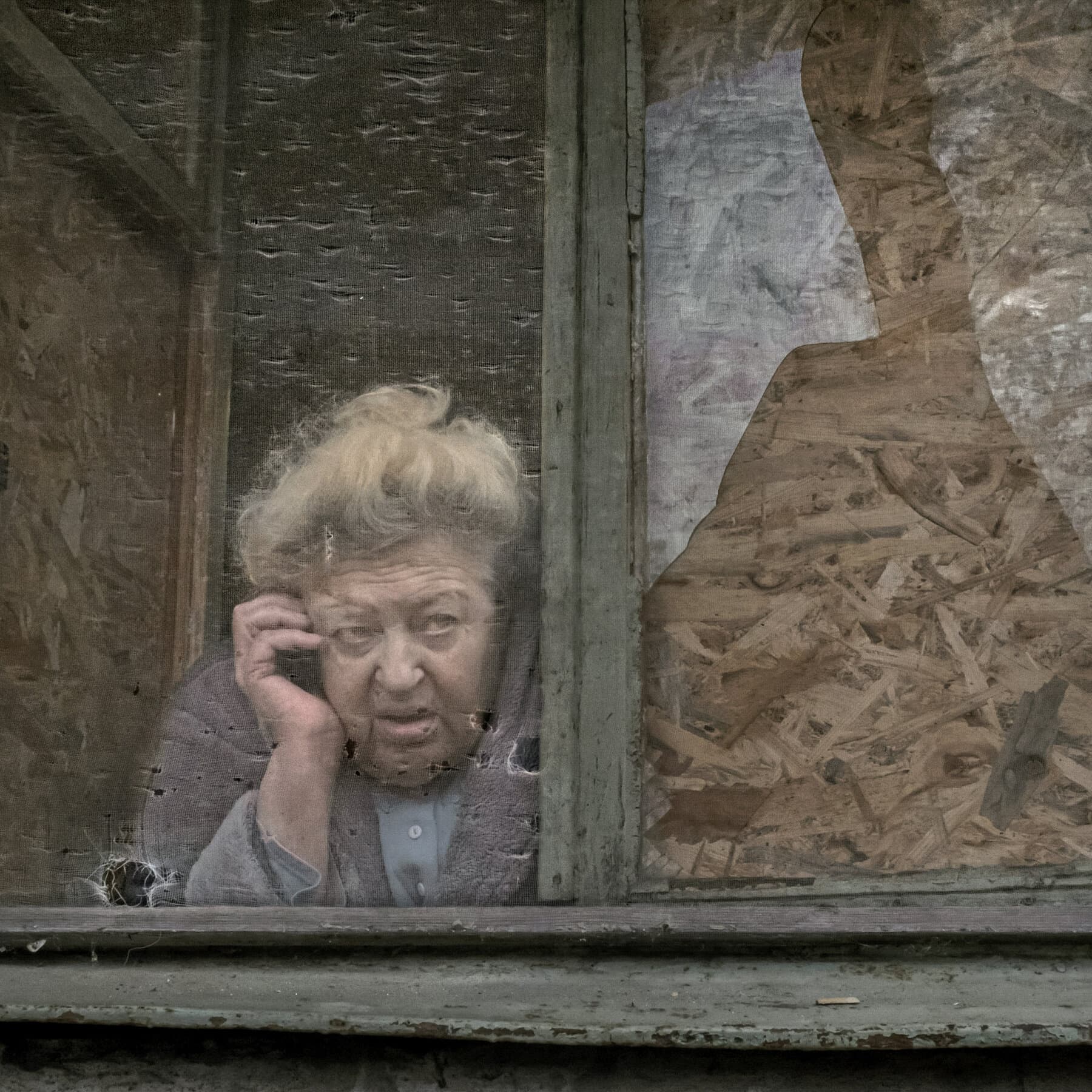A gritty, hyper-realistic scene of a mundane city street in winter, grey and overcast. In the foreground, a child's colorful plastic drone hovers menacingly at eye level, fitted with a dark, crude explosive device. In the background, blurred civilians are rushing into a subway entrance, looking up at the sky in terror. The contrast between the toy-like drone and the terrified adults. Muted colors, cold atmosphere.