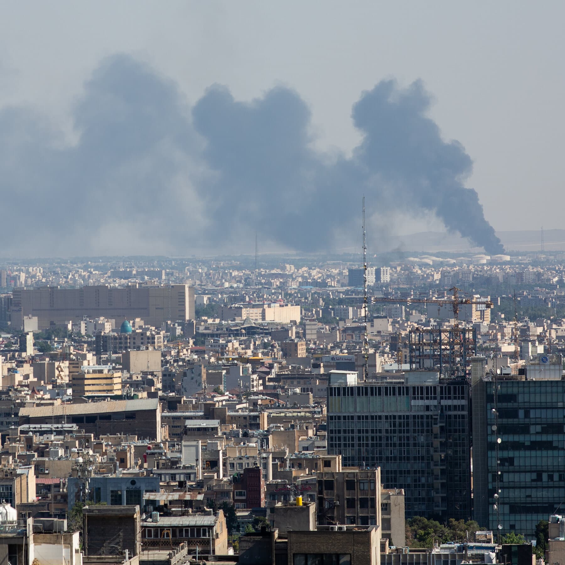 A split screen graphic. On the left, a heavy, dark silhouette of a US aircraft carrier in rough seas. On the right, a tattered Iranian flag waving in smoke. The colors are muted grey and dark red. The style is gritty and realistic.