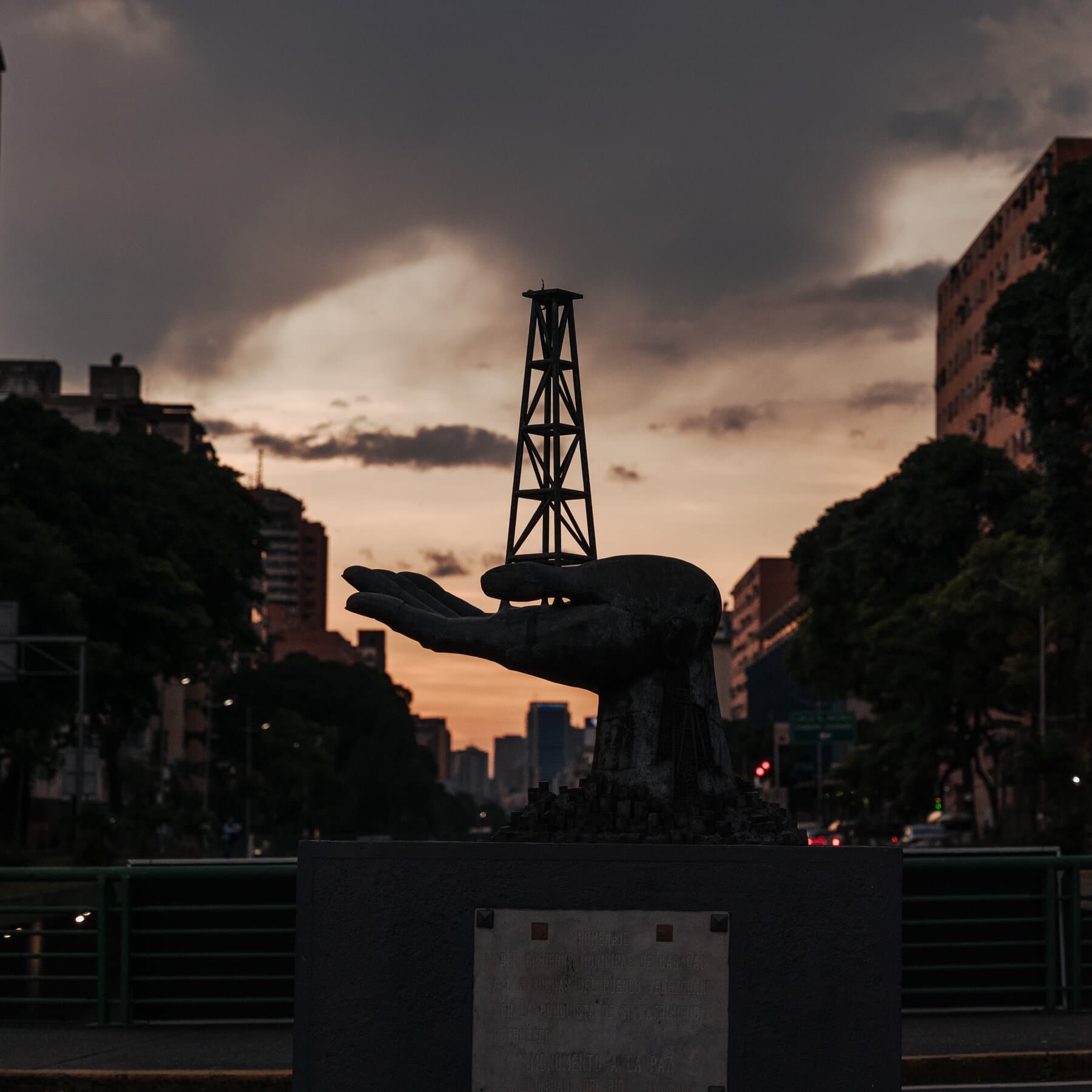 A gritty, high-contrast illustration of a decaying oil rig in Venezuela, with a rusty Venezuelan flag tangled with a pristine American dollar sign, executed in a dark, cynical comic book style.