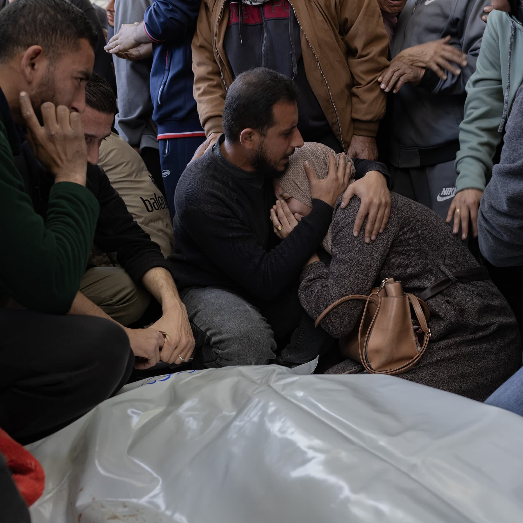 A surreal, gritty political illustration of a giant, ornate metal gate standing alone in the middle of a vast pile of gray rubble. The gate is slightly ajar, revealing a bright, blinding white light, while the surrounding landscape is dark, smoky, and ruined. In the foreground, a single red ribbon is cut, lying in the dust. The style should be high-contrast, noir-inspired, with a cynical and somber mood.