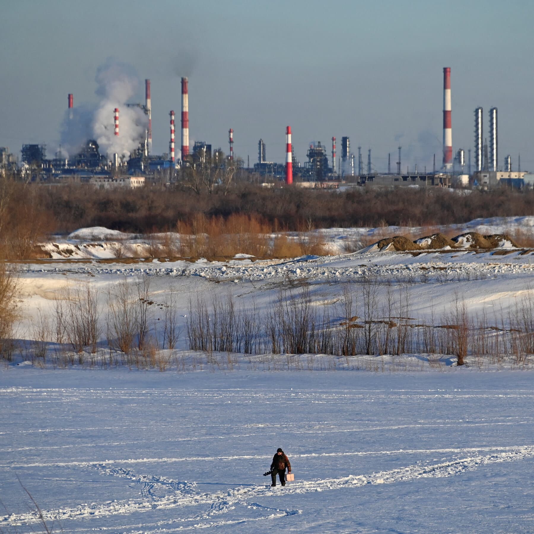 A gritty, high-contrast illustration of a rusted oil pipeline leaking gold coins into dirty snow. In the background, a bleak grey sky hangs over a silhouette of the Kremlin. In the foreground, an empty leather wallet lies open and discarded in the slush. The style should be cynical and dark, resembling a political cartoon with no humor.