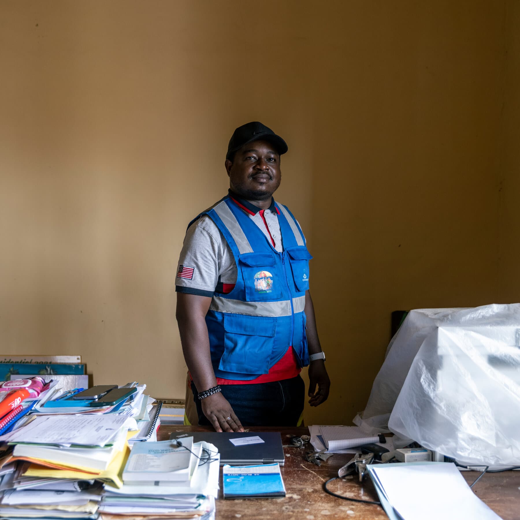 A gritty, high-contrast black and white photo of a dusty, empty medicine bottle lying on cracked dry earth, with a blurred silhouette of a suited politician in the background walking away, style of political satire collage.