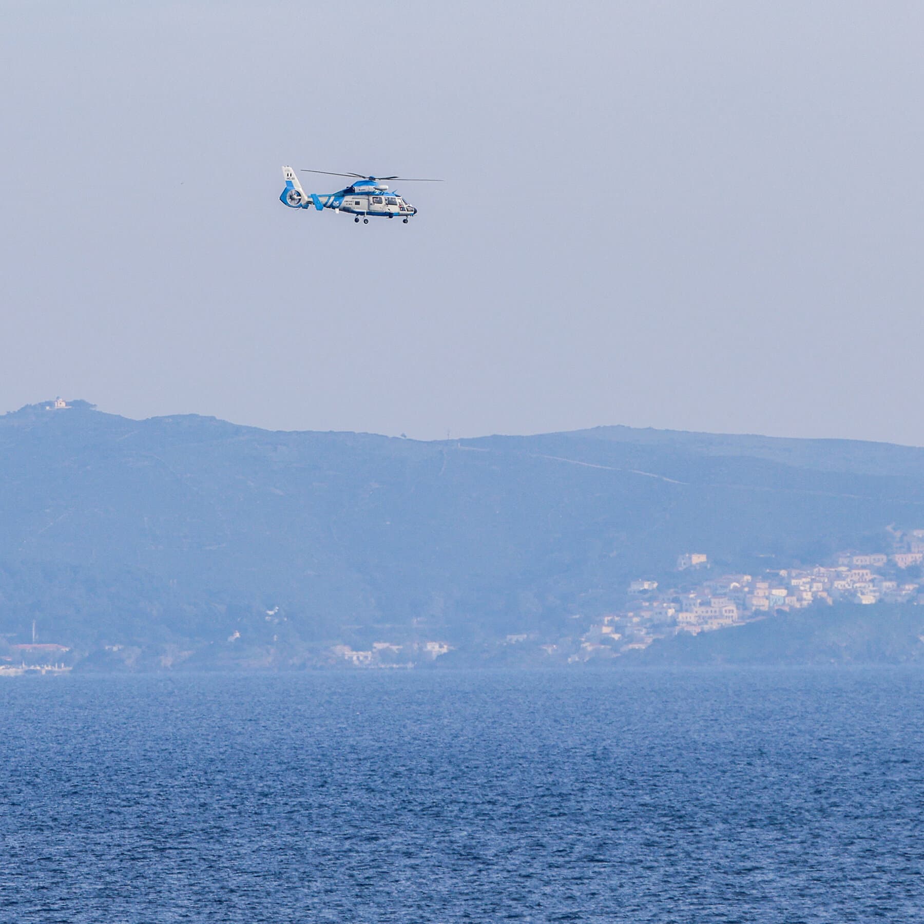 A vast, dark, and empty Mediterranean ocean under a gloomy gray sky. In the center, a single deflated rubber dinghy floats aimlessly, half-submerged. No people are visible, only the vast emptiness of the water. The mood is cold, cinematic, and desolate.
