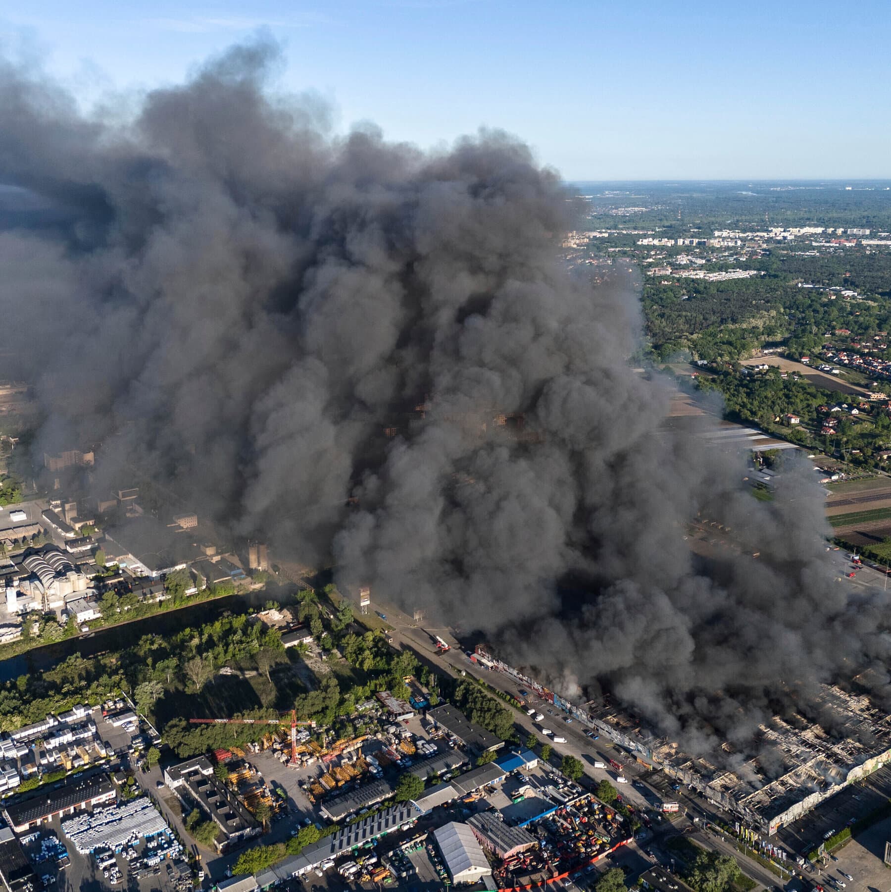 A gritty, noir-style illustration of a nondescript taxi parked on a dark, wet European cobblestone street at night. The driver is a silhouette lighting a cigarette. In the background, a faint fire burns in a warehouse. The mood is cynical, cold, and lonely. High contrast, muted colors.