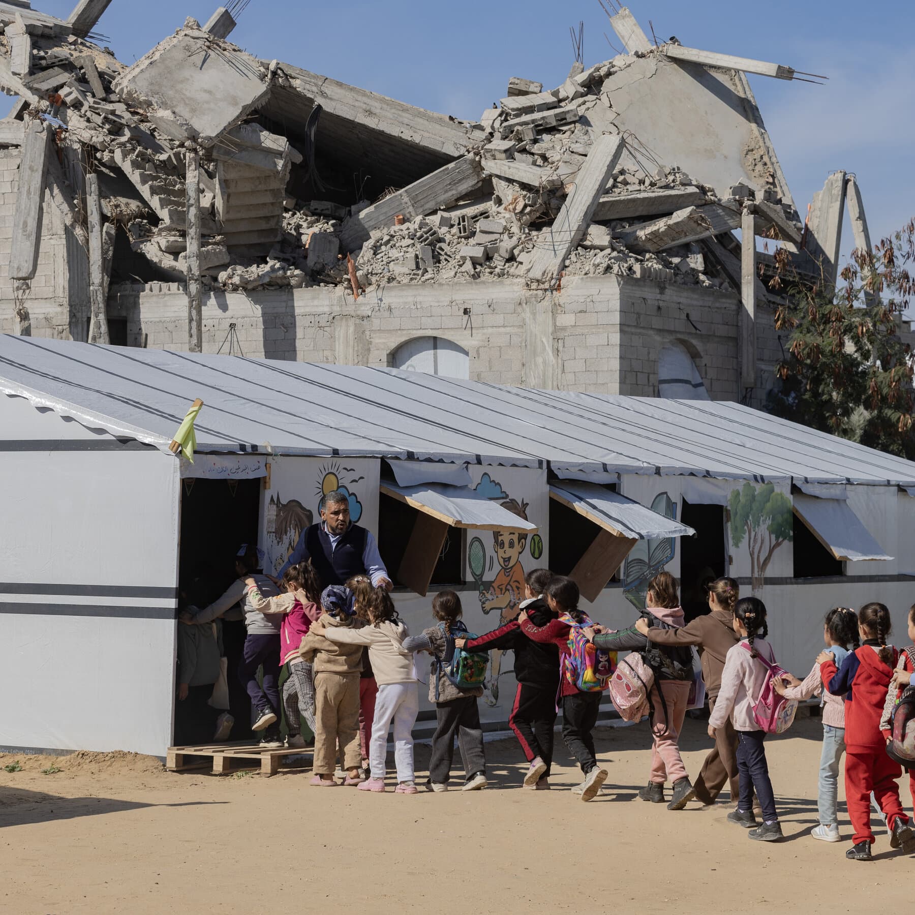 A gritty, hyper-realistic photo of a pristine, colorful school textbook lying open on a pile of dusty grey concrete rubble in a war zone. In the background, blurred silhouettes of ruined buildings against a harsh sky. High contrast, cinematic lighting.
