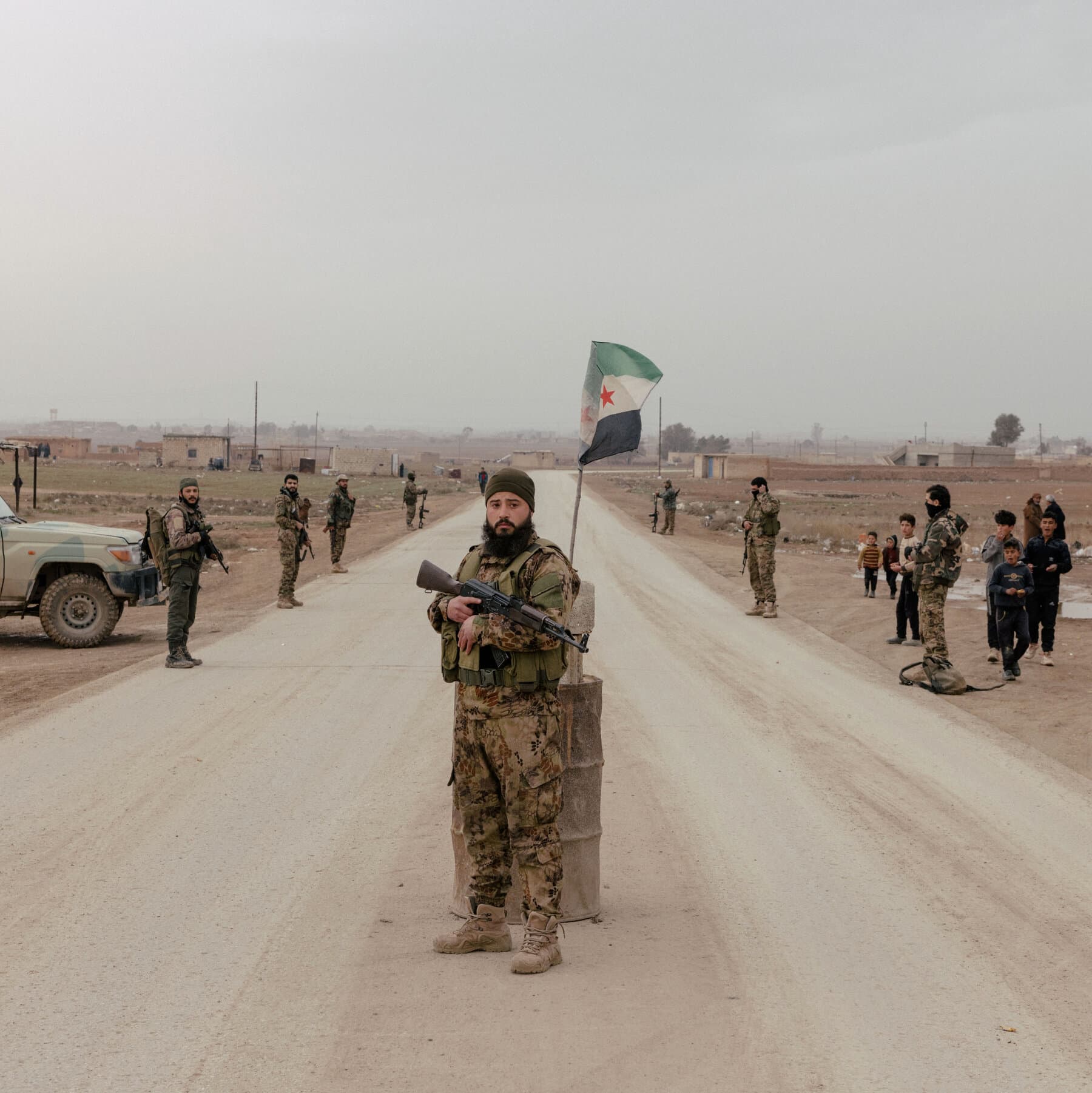 A gritty, high-contrast editorial illustration of a heavy military boot stepping onto a frayed map of Syria. Under the boot, a small, vibrant flower representing Kurdish autonomy is being crushed into the paper. The rest of the map is grey and monochromatic, symbolizing the 'one authority'. The lighting is dim and dramatic, emphasizing a mood of hopelessness and crushed dreams.